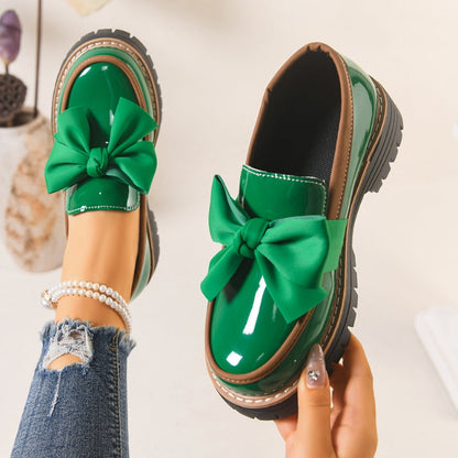 Close-up of Lucente women's loafer showcasing chic bowknot accent on shiny black patent slip-on platform shoe.