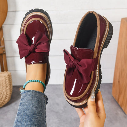 Pair of women's Lucente black patent bowknot loafers, comfortable slip-on flats with a stylish platform sole.