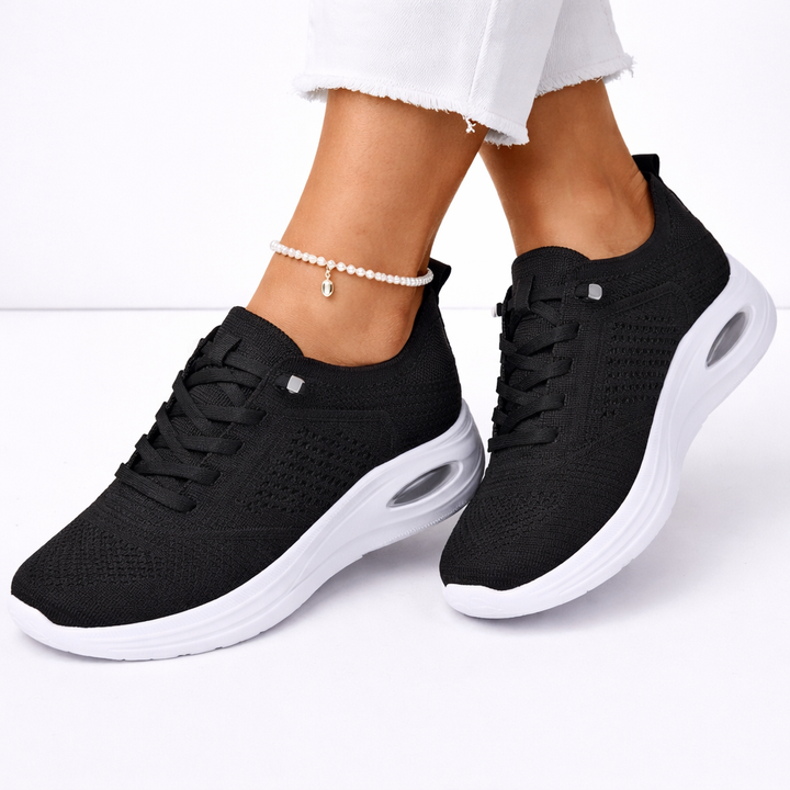 Women's orthopedic slip-on sneakers in black, offering lightweight comfort & foot support for everyday walking.