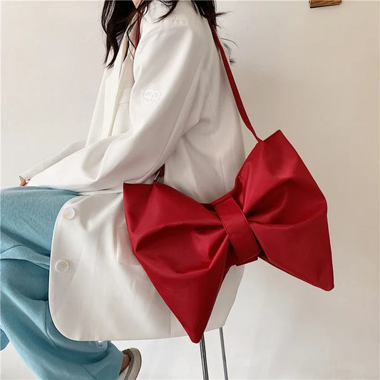 Women's oversized canvas tote bag with large decorative bow. Chic, playful fashion accessory.