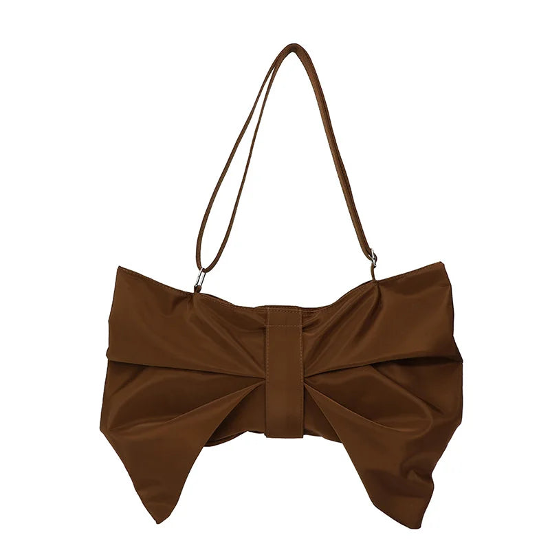 Woman carrying a fashionable oversized bow tote bag. Chic, large canvas handbag for a stylish look.