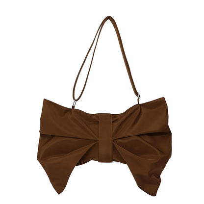 Woman carrying a fashionable oversized bow tote bag. Chic, large canvas handbag for a stylish look.