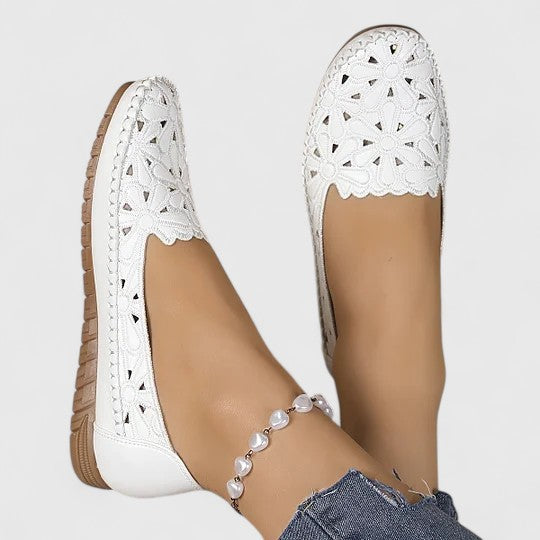 Elegant women's slip-on ballet flats featuring intricate perforated floral cutout design for breathable summer fashion.