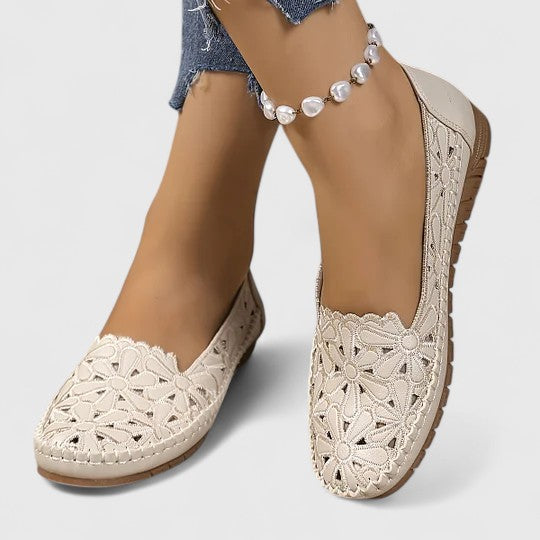 Women's round toe ballet flats with a comfortable slip-on fit, elegant floral cutout, and scalloped edge detail.