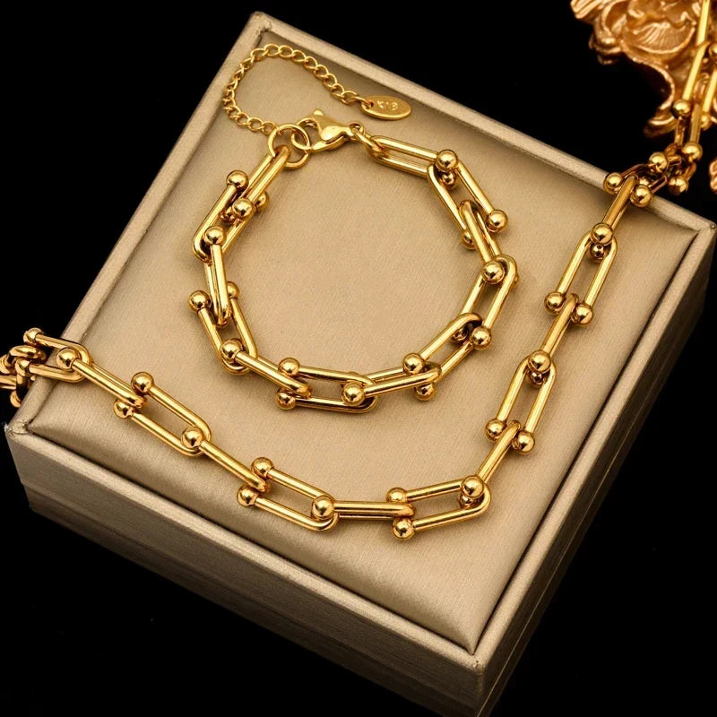 Women's fashion model wearing elegant gold link chain necklace & bracelet jewelry set.