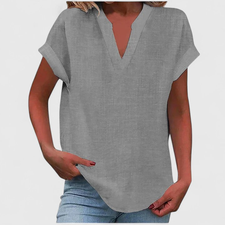 Stylish V-neck relaxed blouse for women, featuring a comfortable fit, cap sleeves, and curved hem.