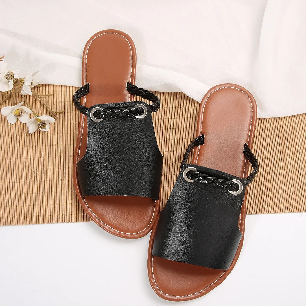Casual women's footwear: classic black braided slip-on flat sandals for summer.