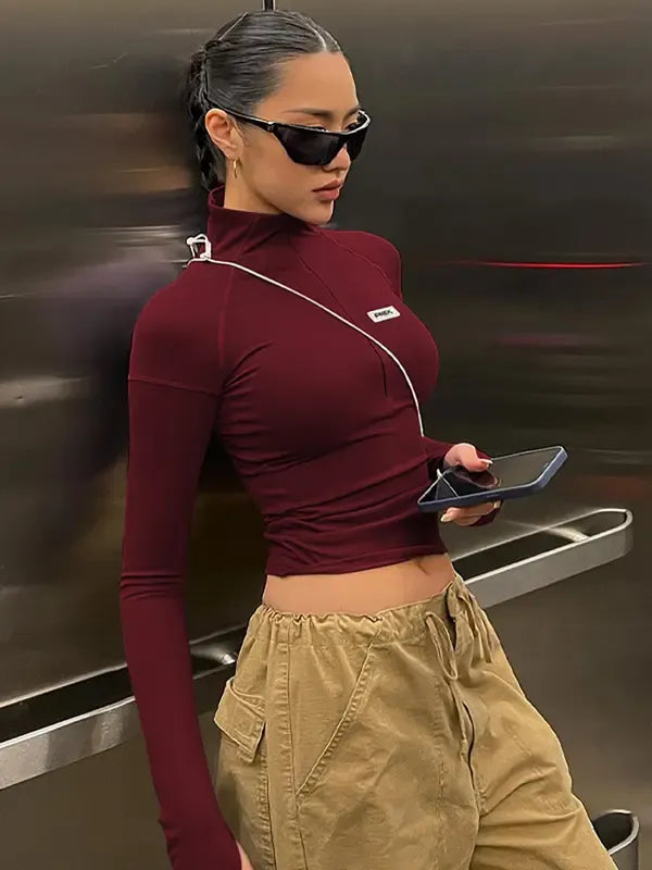 Women's sculpting long sleeve zip crop top in black. Perfect for modern, fitted everyday style.
