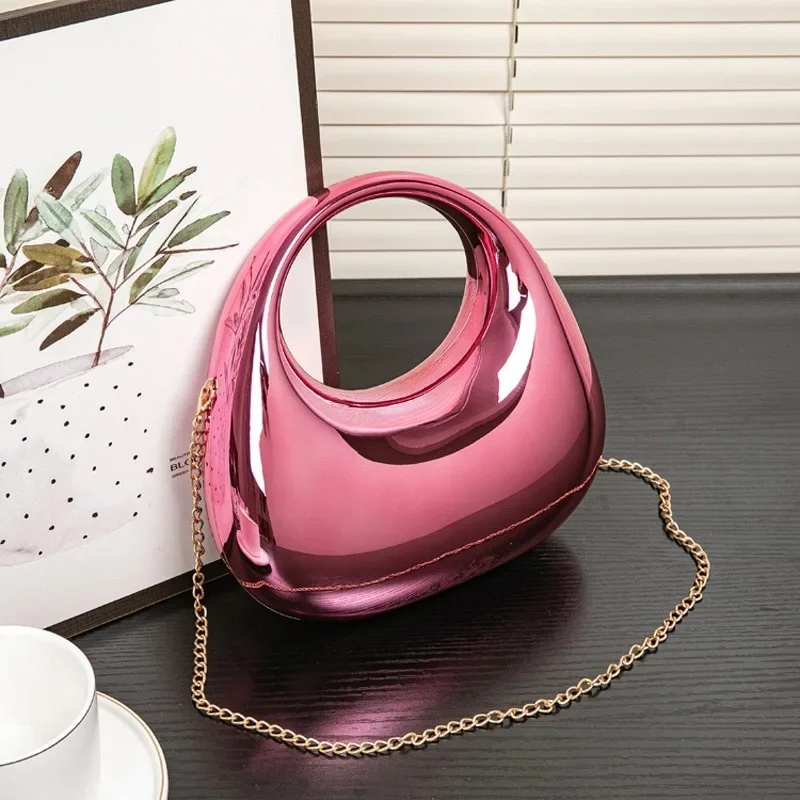 Designer women's clutch, sculptural shape, sophisticated mirror finish.