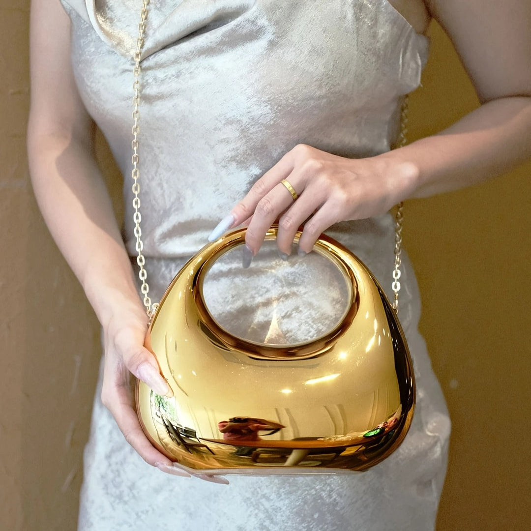 Modern women's accessory: sculptural clutch bag with a high-shine mirror finish.