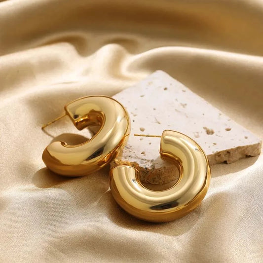 Women's sculptural hoop earrings in elegant gold and silver finish, a stylish fashion accessory.