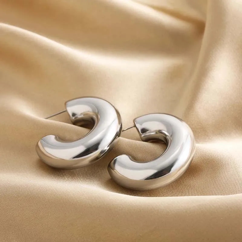 Elegant sculptural hoops, women's statement earrings with shimmering gold and silver finish for shine.