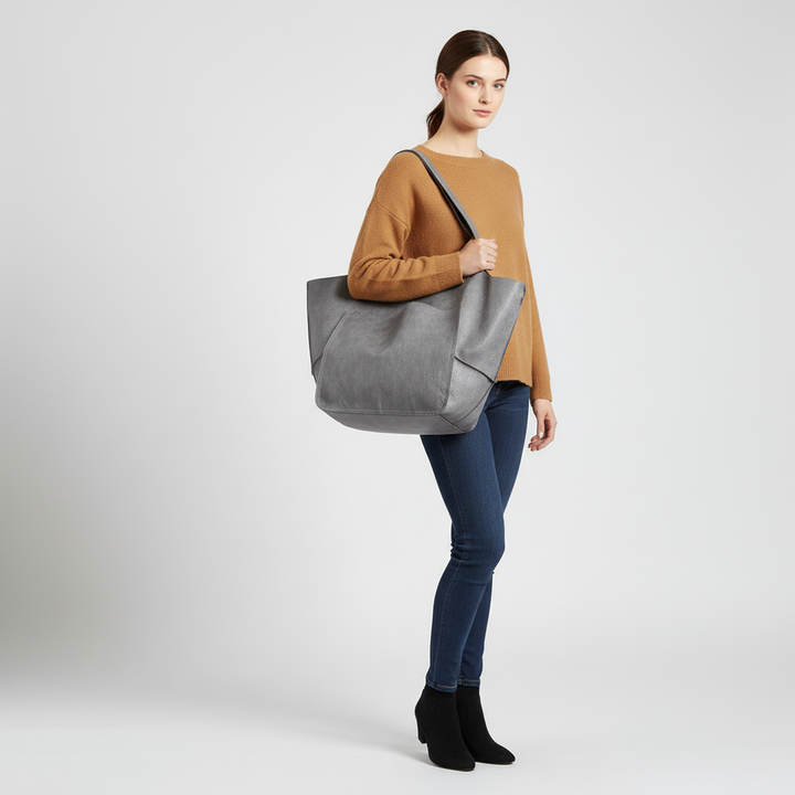 Woman carrying a large capacity vegan leather tote bag, showcasing its comfortable shoulder strap & stylish design.