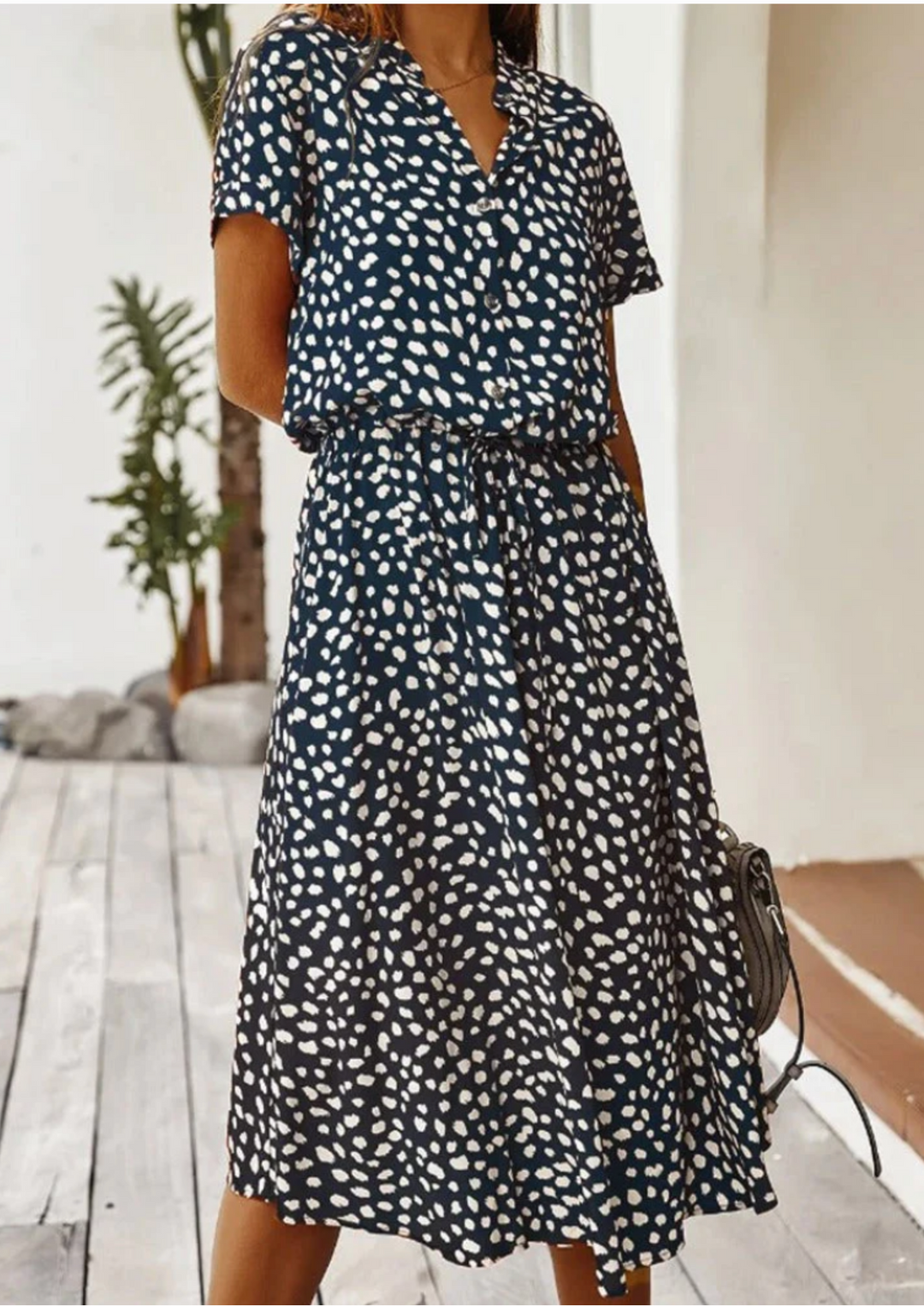 Casual women's spotted print midi dress, featuring button detailing, a V-neck, and flowy skirt.