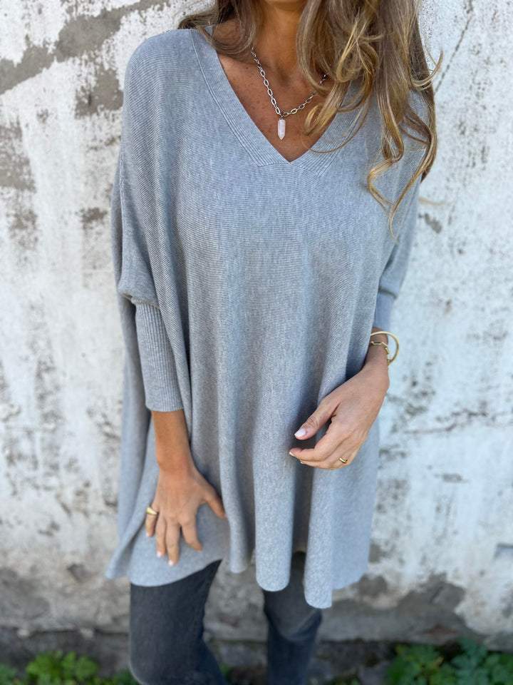 Stylish V-neck tunic sweater for women, featuring a swing hem & cozy batwing long sleeves. Versatile pullover.