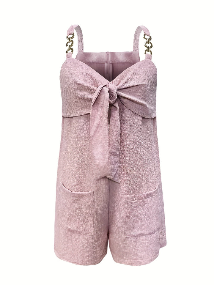 Sophisticated evening wear: black textured romper with elegant chain straps & a bow detail.