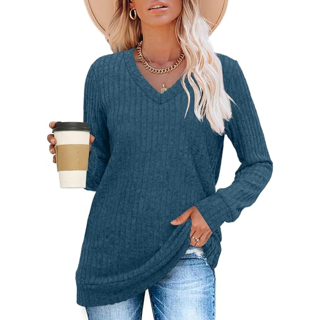 Model relaxing in women's V-neck tunic sweater, showcasing its lightweight comfort & casual appeal.