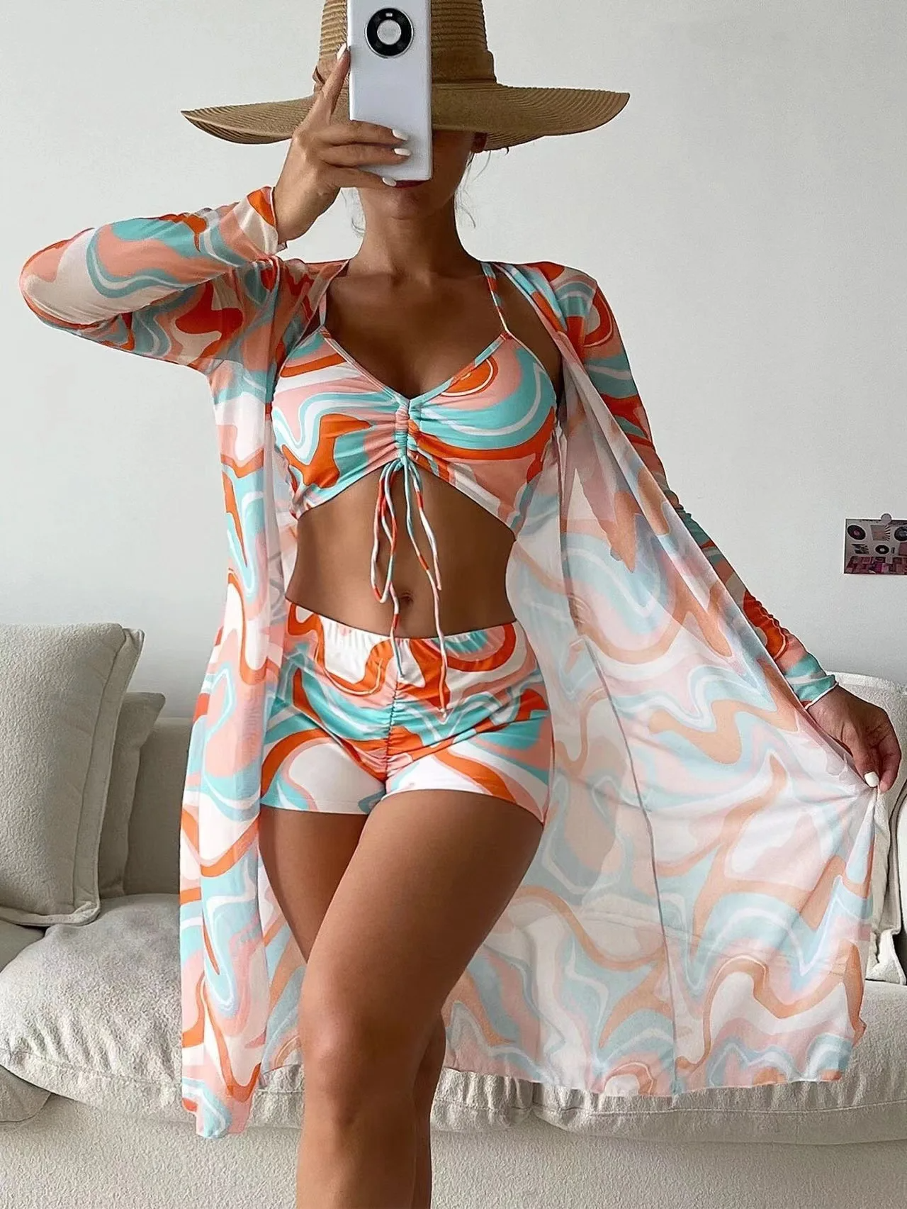 Back view of a vibrant women's 3-piece swimsuit set with a stylish mesh cover-up.