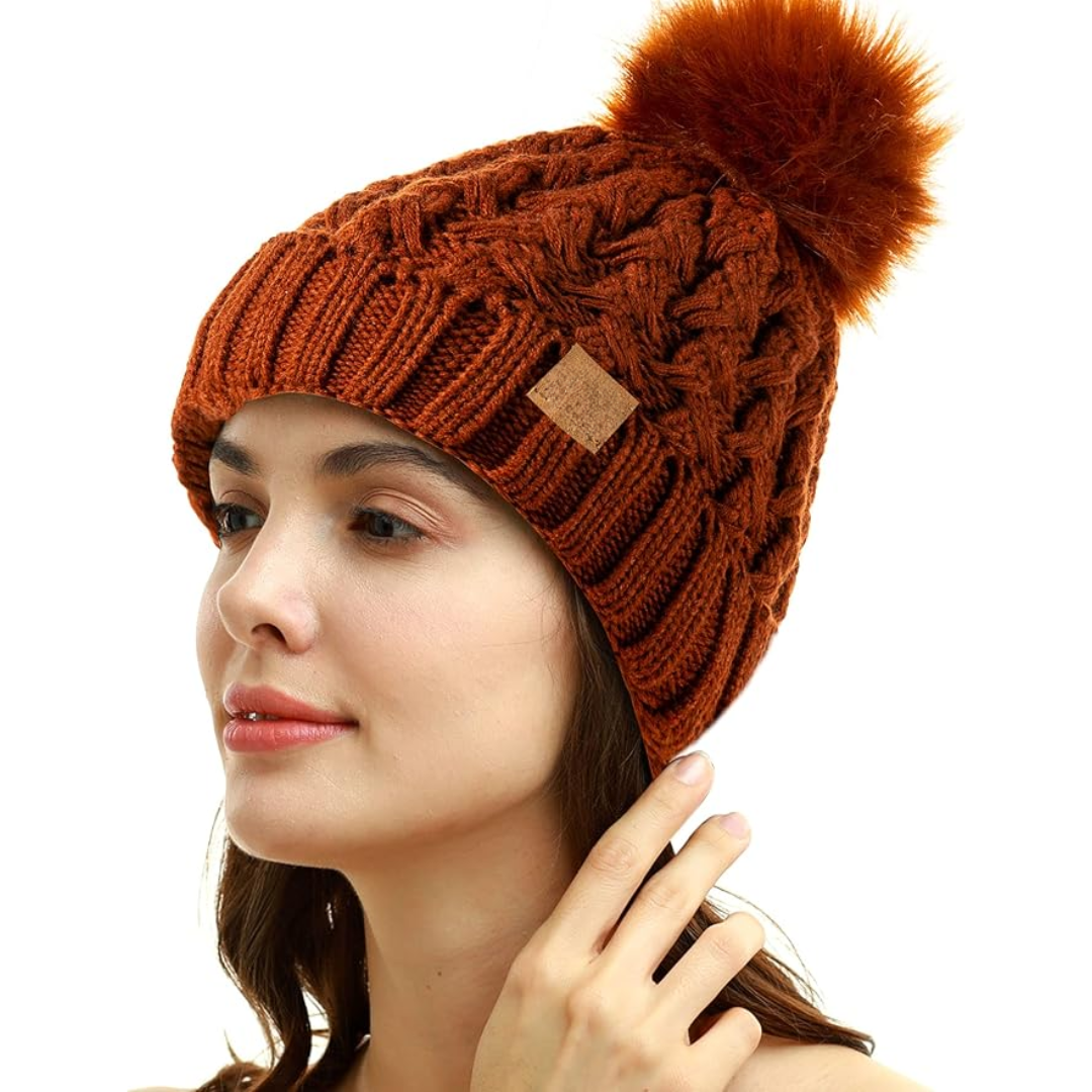 Close-up of women's cable knit beanie texture, fleece-lined, with a fluffy pom-pom.