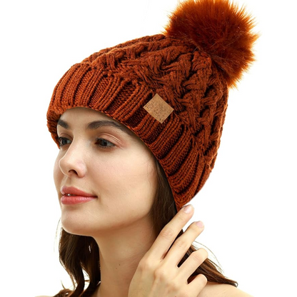 Close-up of women's cable knit beanie texture, fleece-lined, with a fluffy pom-pom.