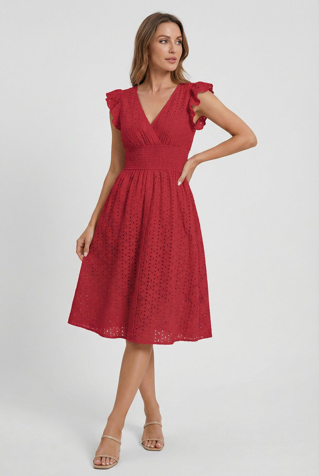 Woman comfortably seated in a flattering flared eyelet midi dress with ruffled sleeves & smocked waist. Summer ready.