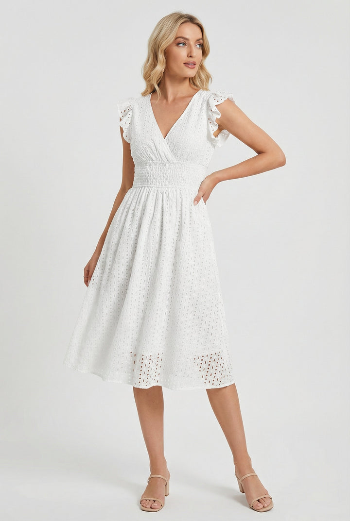 Close-up of delicate eyelet fabric on a women's white midi dress. Features ruffled sleeves & smocked waist for summer.