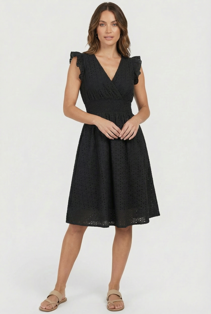 Woman in chic white eyelet midi dress with ruffled sleeves. Great as a beach dress or casual summer outfit.