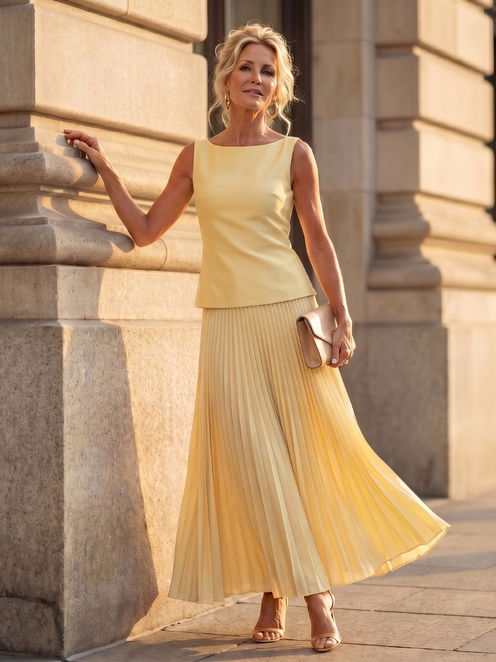 Women's yellow structured bodice top & pleated maxi skirt two-piece set, elegant summer outfit.