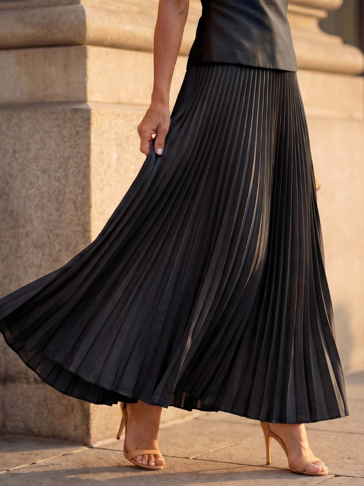 Yellow sleeveless women's skirt set with a structured top and an elegant pleated maxi skirt.