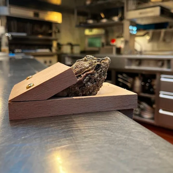 Securely shuck oysters with this wooden clamp, a safe & easy seafood opener kitchen tool.