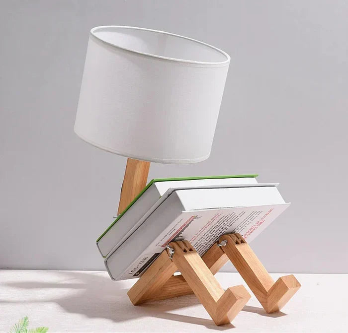 Adjustable wooden robot table lamp providing unique lighting, featuring a handy integrated book holder.